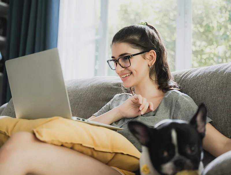 En kvinna sitter i soffan och gör en konsultation för tandställning online